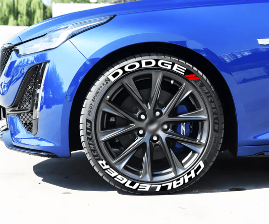 Close-up of a blue sports car featuring ChroMorpher 3D Raised Tire Lettering decals on the sidewall. The bold white "DODGE" and "CHALLENGER" text, along with red accent stripes, enhance the aggressive and high-performance look of the vehicle.