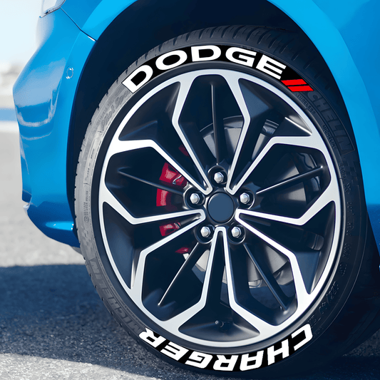 Close-up of a blue Dodge Charger with ChroMorpher 3D Reflective Tire Lettering decals applied to the tire sidewall. The bold white "DODGE" and "CHARGER" text, along with red accent stripes, give the vehicle a sporty and race-inspired look.