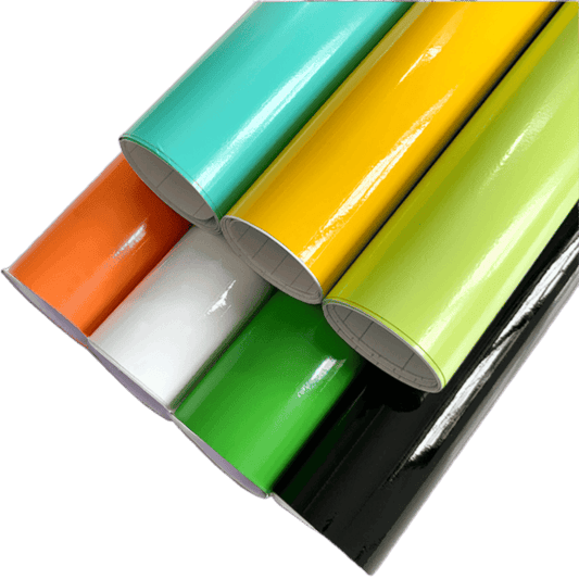 A collection of vibrant ChroMorpher Colorful Gloss Vinyl Rolls in various colors including orange, white, green, black, yellow, and mint, showcasing their glossy finish and high-quality material.