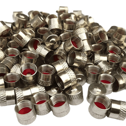 A large pile of silver-colored metal tire valve caps with a knurled grip texture and red rubber seals inside. The caps are designed for protecting tire valves from dust, dirt, and moisture while ensuring a secure fit. The high-quality metal finish gives them a durable and premium look. The image has a transparent background, highlighting the details of the caps.