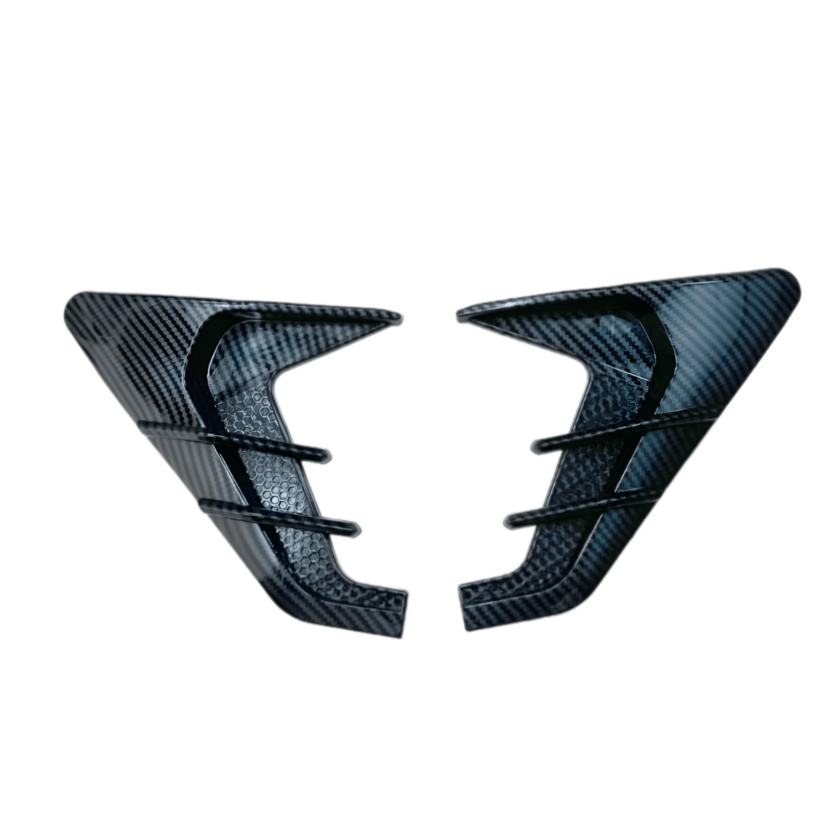 A pair of ChroMorpher Side Fender Vents in a Carbon Look finish, displayed on a transparent background. These vents feature a detailed carbon fiber pattern for a sleek, high-performance aesthetic. Designed to enhance the vehicle's aggressive and sporty appearance, they are made from durable, weatherproof rubber for long-lasting performance. The textured honeycomb details add depth to the design, making them a stylish upgrade for any car. With a self-adhesive backing, they allow for easy, drill-free installa