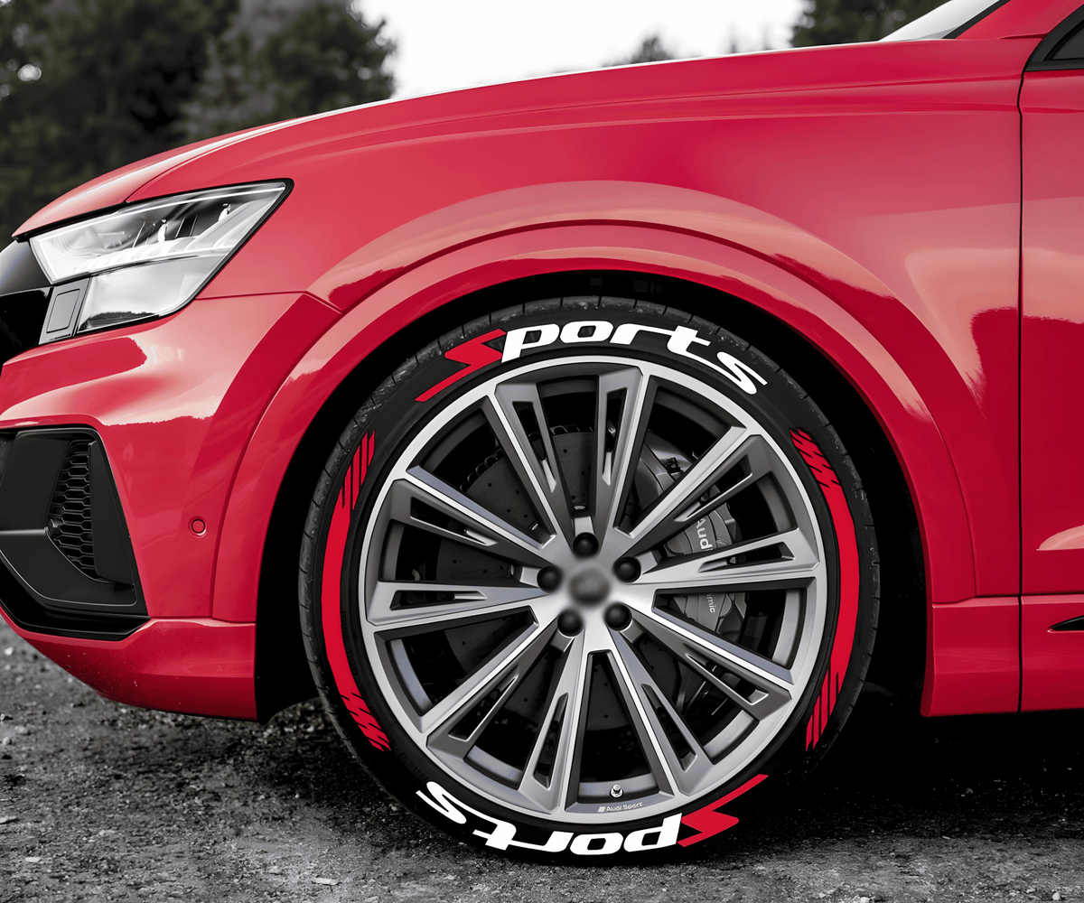 Close-up of a red sports car with ChroMorpher SportsX Tire Lettering applied to the tires, featuring bold white "Sports" text and red racing accents. The decals enhance the high-performance aesthetic of the wheels, giving the car a dynamic and aggressive look.