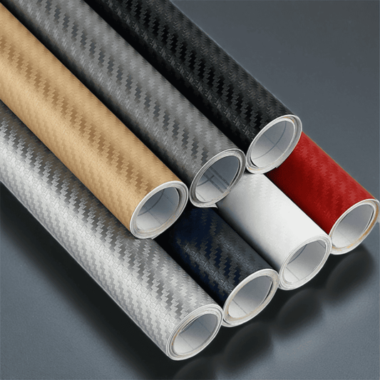 Rolls of ChroMorpher Wide Carbon Vinyls in various colors including gold, silver, black, white, red, and blue, featuring a realistic 3D carbon fiber texture. Ideal for vehicle customization and other surfaces