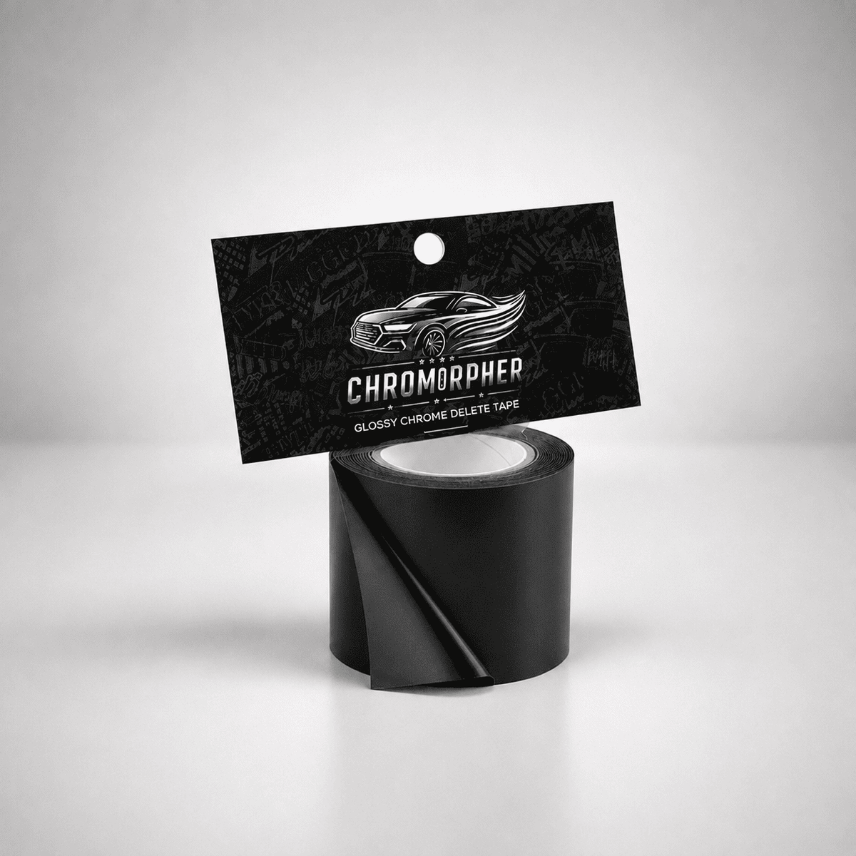A roll of black glossy chrome delete tape with its black hanging card packaging, featuring the brand name 'CHROMORPHER' and a car graphic, set against a light gray studio background.