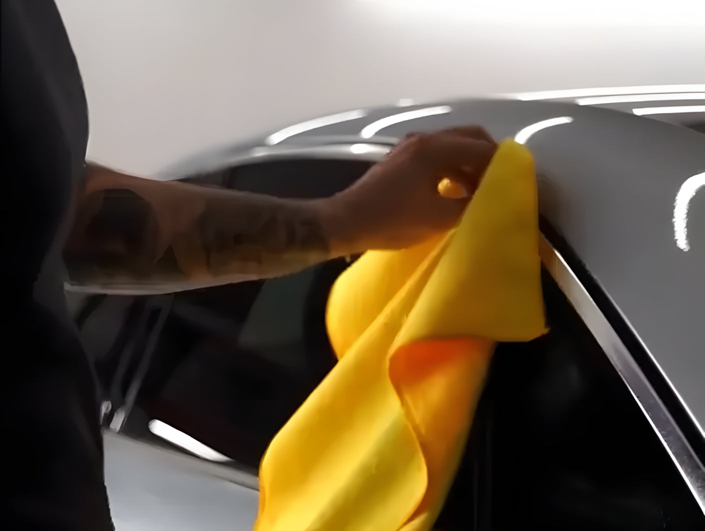 Person cleaning chrome window trim with a microfiber cloth before applying ChroMorpher Chrome Delete Tape.