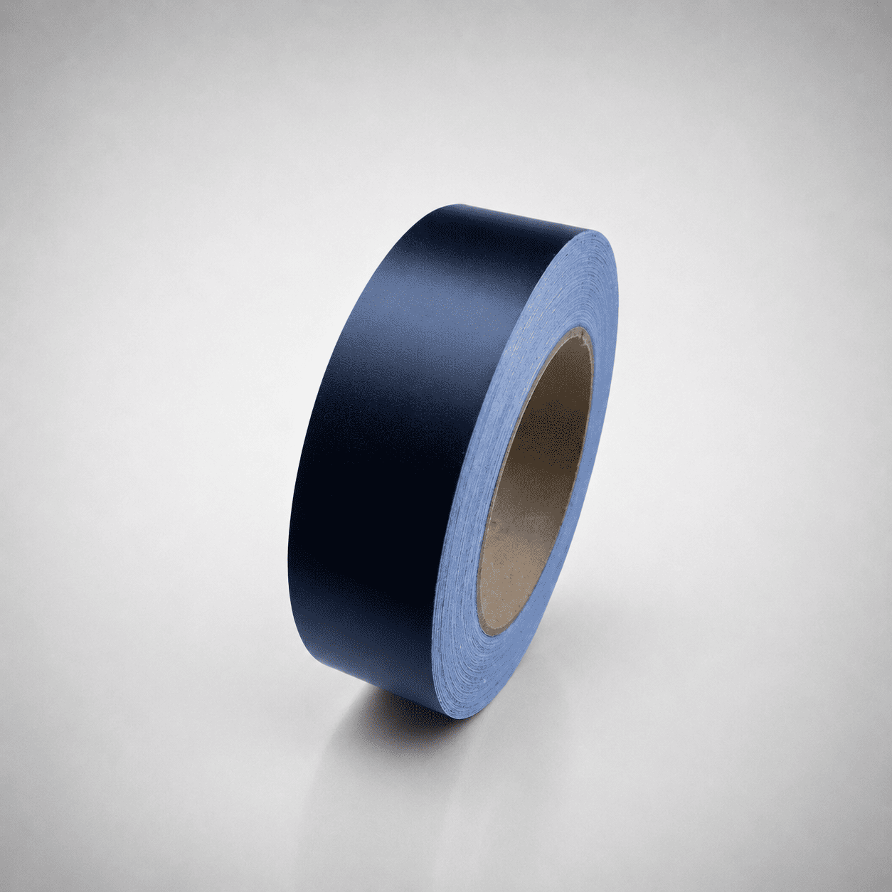 A roll of dark black matte tape standing upright on a light gray gradient background.