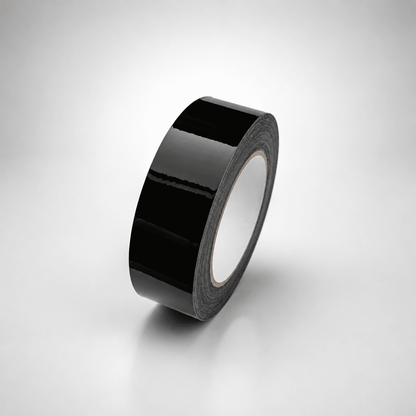 A roll of glossy black tape standing upright on a light gray gradient background.