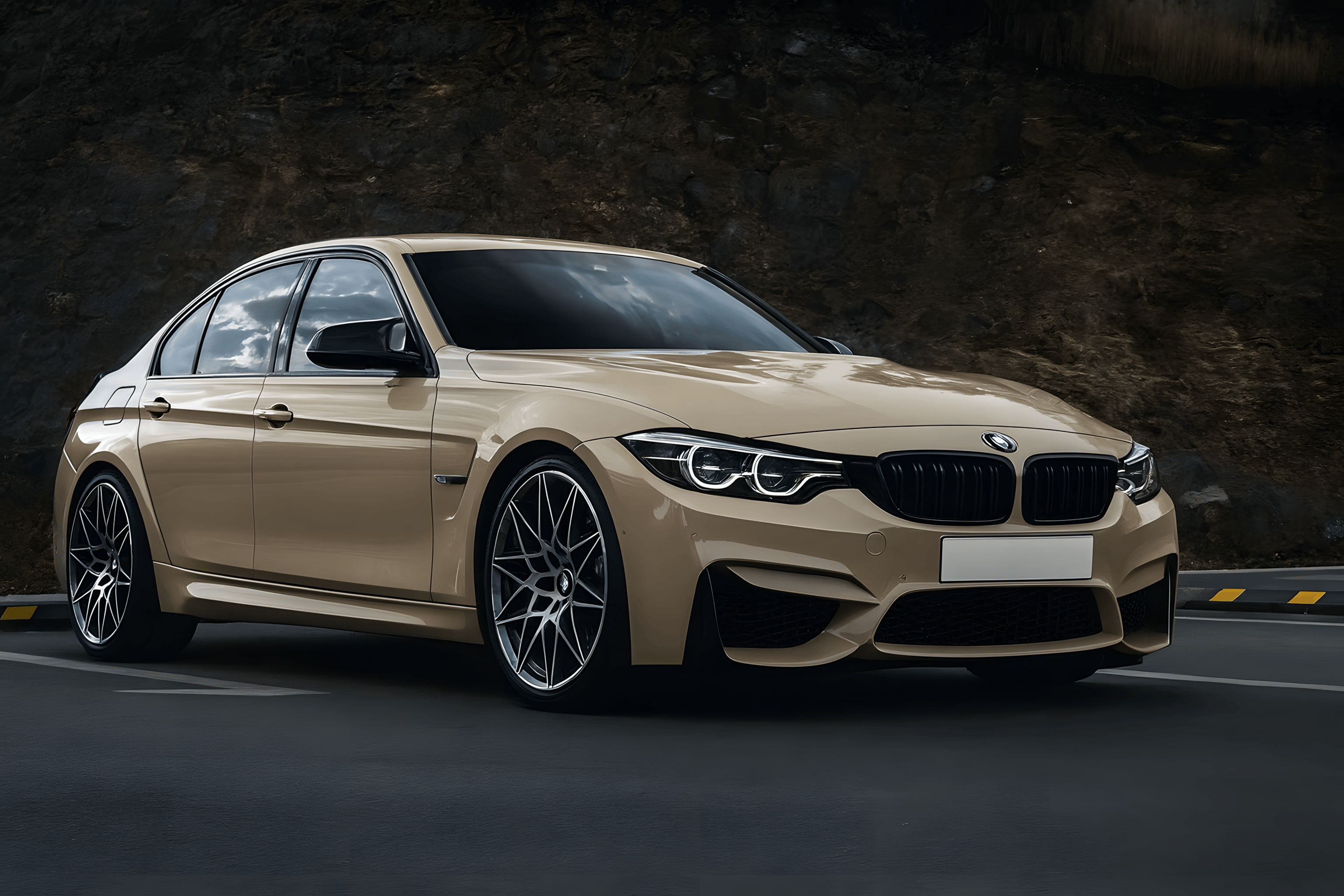 Beige BMW M3 with glossy black window trims and blacked out grille parked in a rocky parking area, showcasing a clean chrome delete finish.