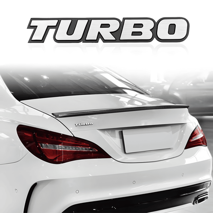 ChroMorpher 3D Metal TURBO Emblem installed on the rear of a white car. The emblem features bold, shiny letters with the word "TURBO" designed in a sleek, chrome-like finish.