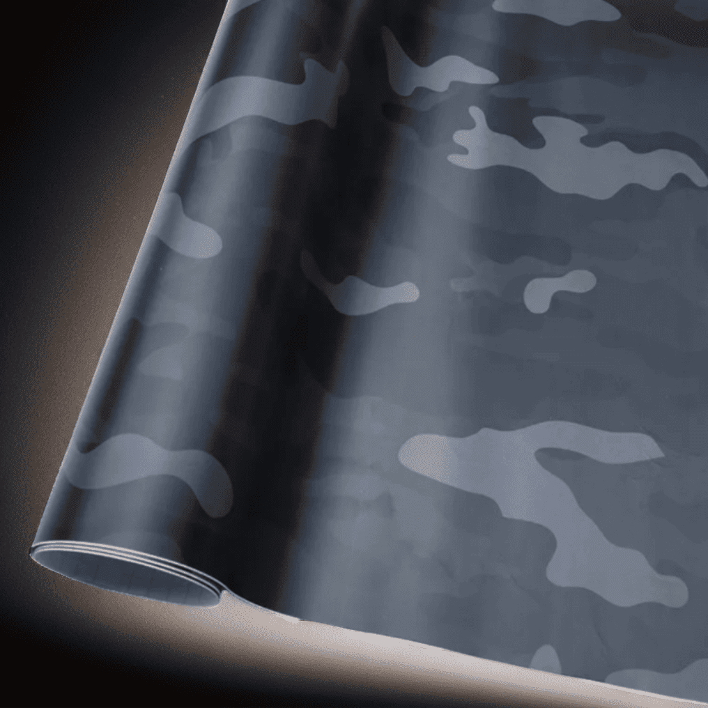 A roll of ChroMorpher black camo vinyl wrap, featuring a sleek camouflage pattern in matte and glossy finishes, ideal for creating a distinctive and stylish look on vehicles and custom surfaces.