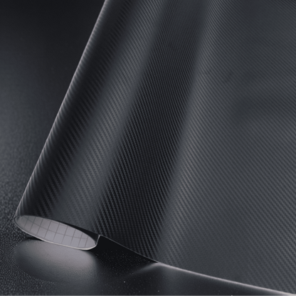 A roll of ChroMorpher black carbon fiber vinyl wrap, showcasing a detailed and realistic 3D carbon fiber texture, ideal for adding a sleek and modern finish to vehicles and various surfaces.