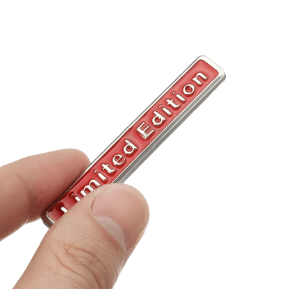 ChroMorpher Limited Edition 3D Metal Emblem held in hand, showcasing its sleek red design on a silver metal background.