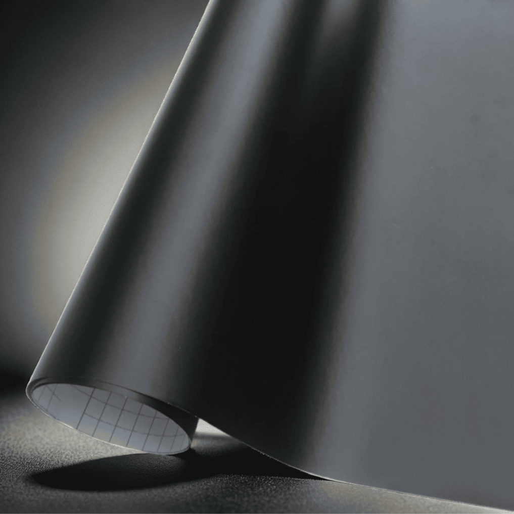 A roll of ChroMorpher matte black vinyl wrap, showcasing a smooth and refined finish perfect for a sleek, understated look on vehicles, furniture, and other customizable surfaces.