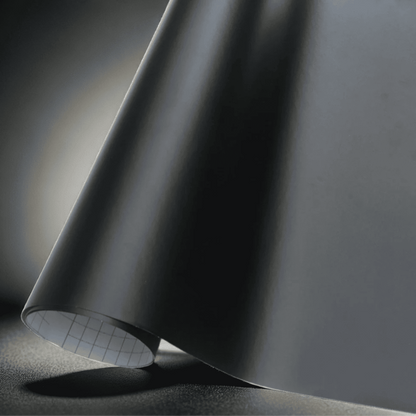 A roll of ChroMorpher matte black vinyl wrap, showcasing a smooth and refined finish perfect for a sleek, understated look on vehicles, furniture, and other customizable surfaces.