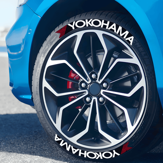 Close-up of a blue sports car with Yokohama 3D tire lettering decals applied to the tires. The bold white Yokohama logo with a red accent enhances the sporty and high-performance aesthetic of the wheel. Perfect for JDM and racing enthusiasts looking to customize their ride.