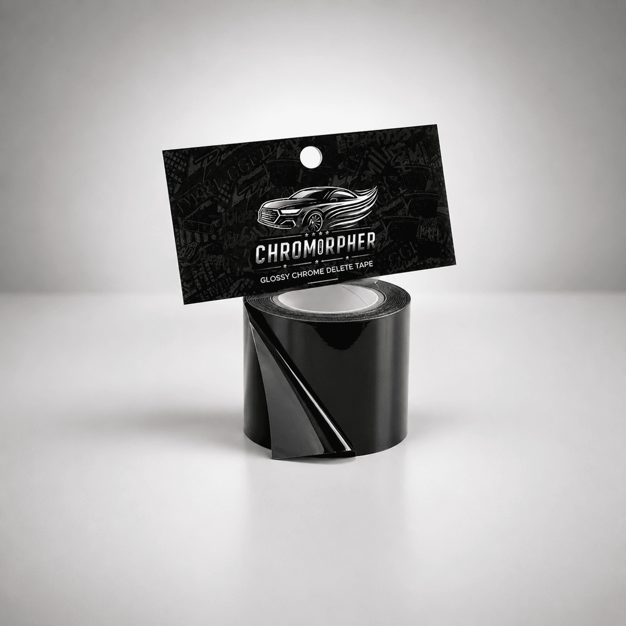 A roll of glossy black chromapher tape with its black hanging card packaging, featuring a silver car graphic and the brand name 'CHROMOPHER', set against a clean gray studio background.
