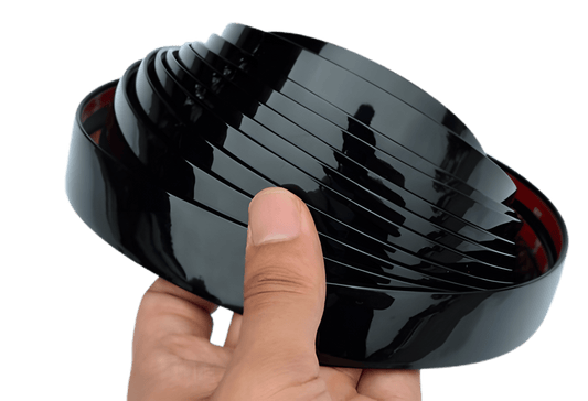 Hand holding a glossy black ChroMorpher Clip-On Trim Cover 2.0 roll showing the high-gloss finish and flexible design