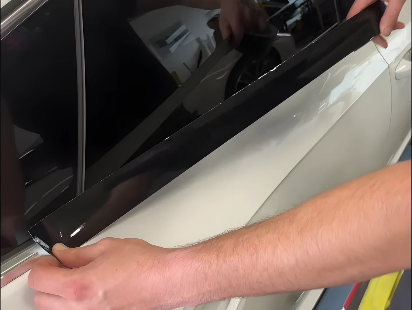 Person cleaning chrome window trim with a microfiber cloth before applying ChroMorpher Chrome Delete Tape.
