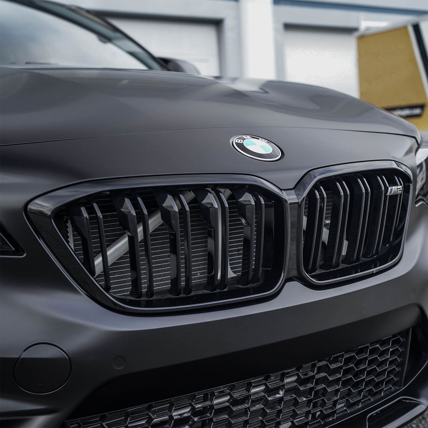 Front view of a BMW grille, showcasing a matte black finish achieved using ChroMorpher chrome delete tape.
