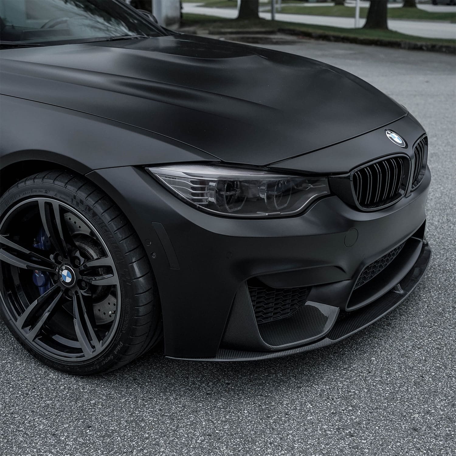 Close-up of a BMW front, showcasing the sleek matte black finish and detailed headlight design.