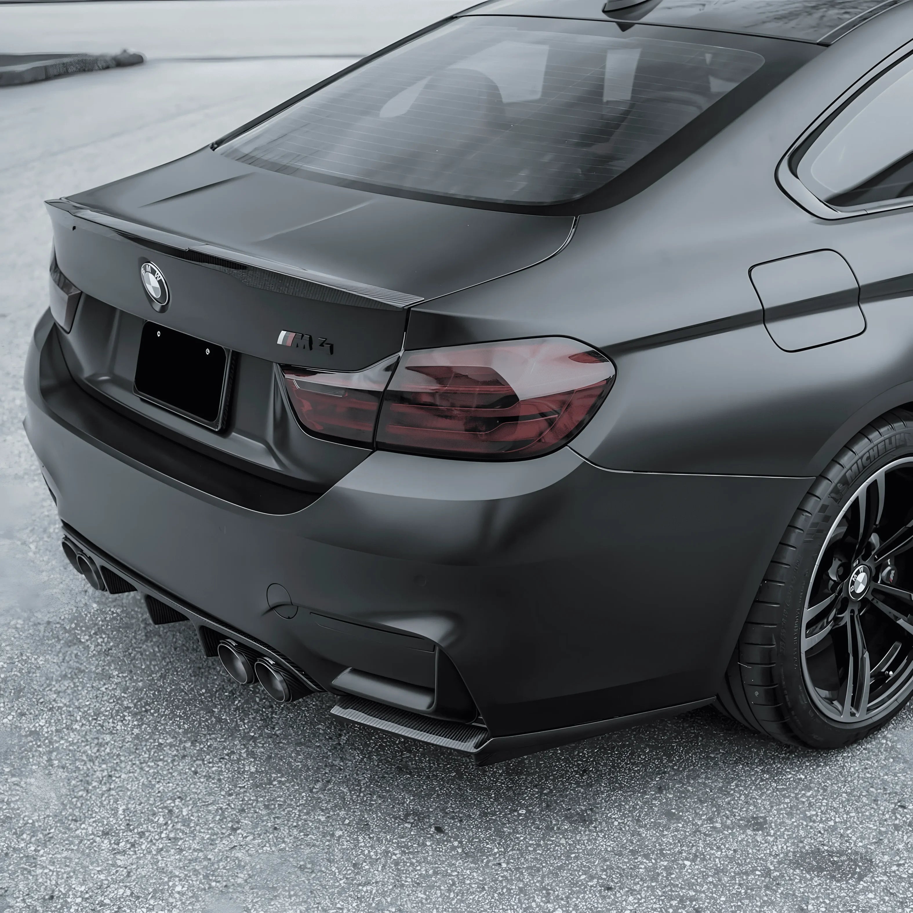 Rear view of BMW M4 with full blackout trim using ChroMorpher Matte Black Chrome Delete Tape and carbon fiber spoiler.