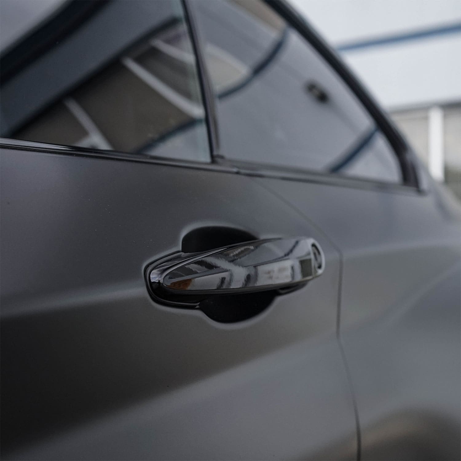 Chrome deleted matte black car door handle using ChroMorpher tape for a sleek finish.
