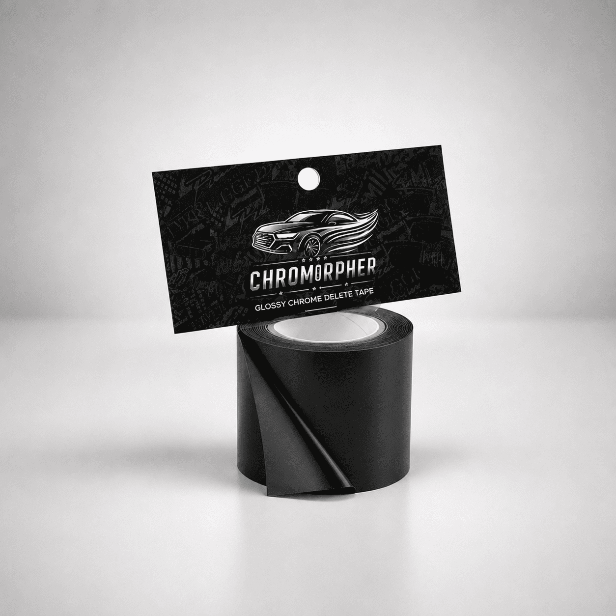 A roll of black glossy chrome delete tape with its black hanging card packaging, featuring the brand name 'CHROMORPHER' and a car graphic, set against a light gray studio background.