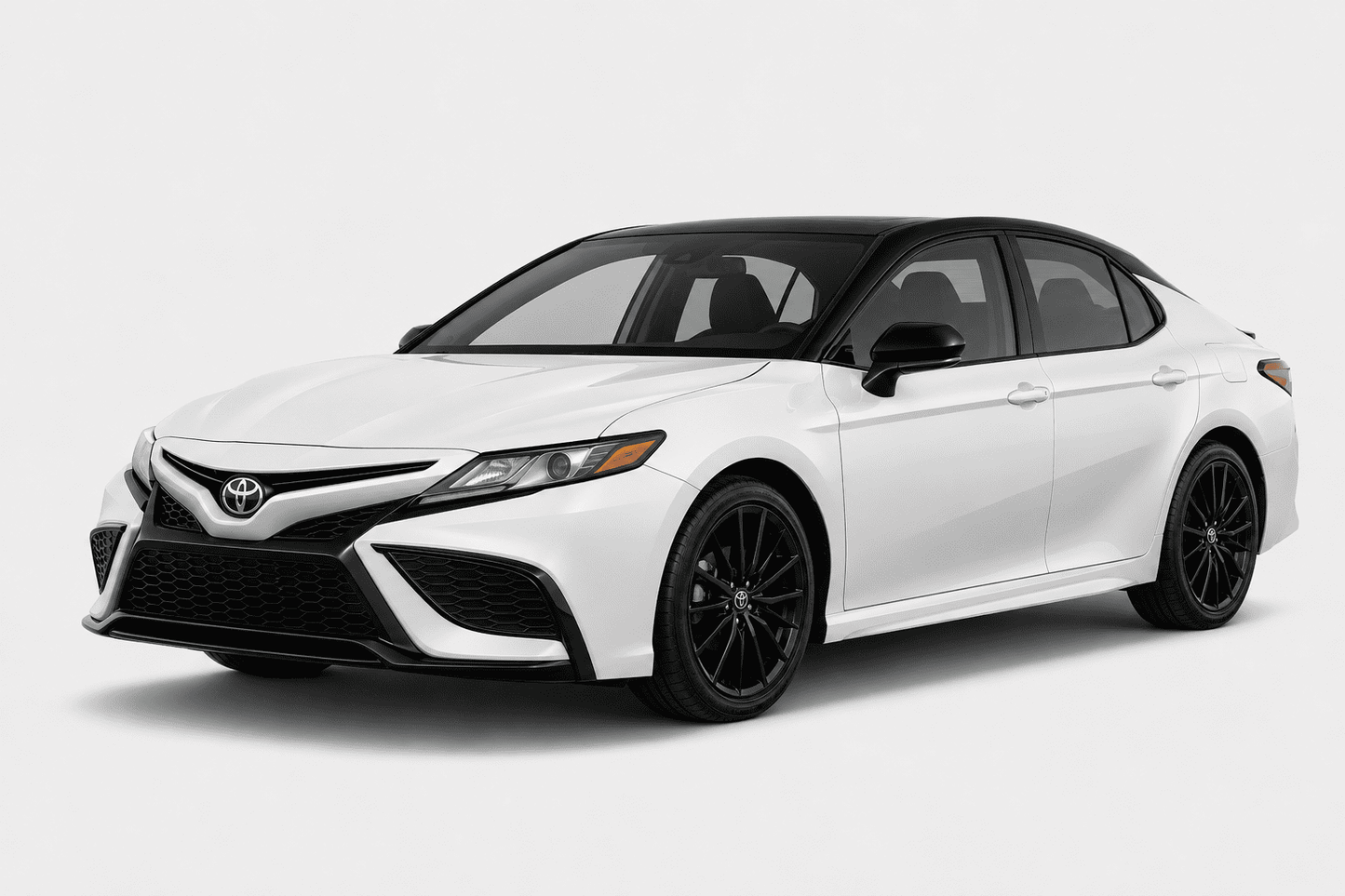 A white Toyota Camry sedan with black accents, including the roof, side mirrors, and wheels, shown from a three-quarter front angle on a light gray studio background.
