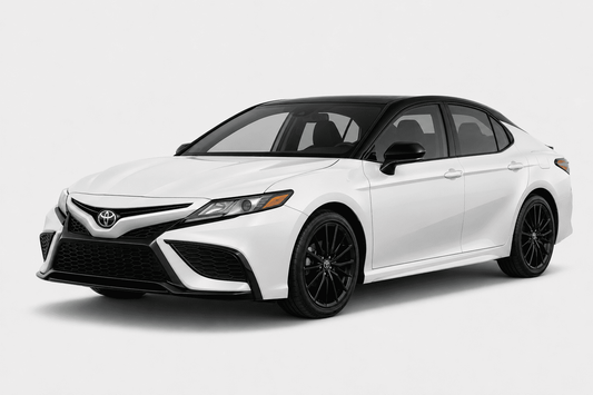 A white Toyota Camry sedan with black accents, including the roof, side mirrors, and wheels, shown from a three-quarter front angle on a light gray studio background.