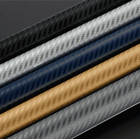 Close-up view of ChroMorpher carbon vinyl rolls in black, silver, blue, gold, and gray, featuring high-quality 3D carbon fiber textures for customizable and durable surface applications.