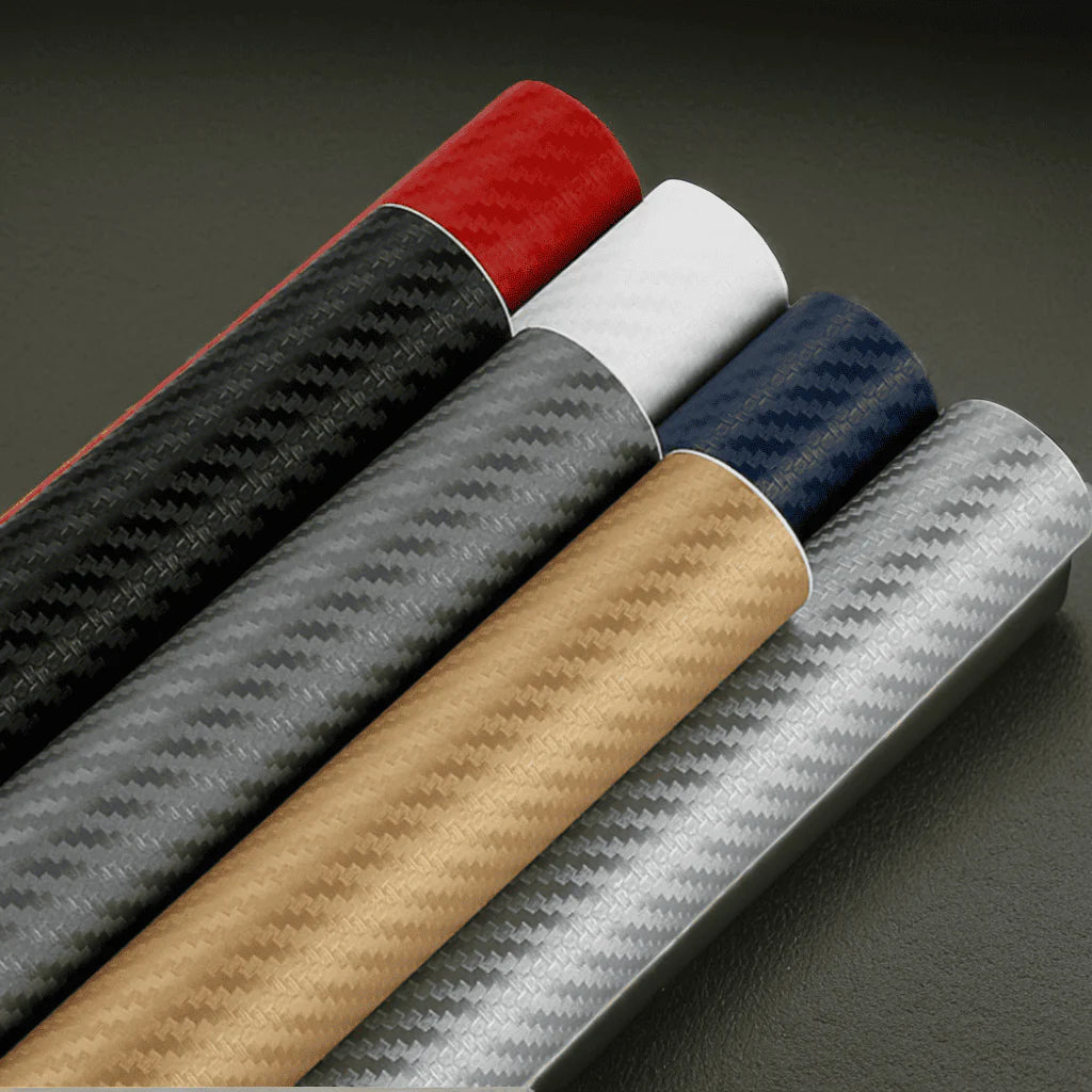 A collection of ChroMorpher carbon vinyl rolls in black, red, white, blue, gold, and silver, featuring realistic 3D carbon fiber textures for sleek and durable vehicle or surface customization.